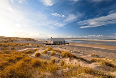 Haus am Strand in Dünenlandschaft bei Sonnenschein.
