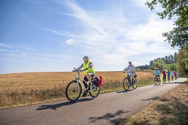 Gruppe von Radfahrern auf ländlichem Weg bei sonnigem Wetter.