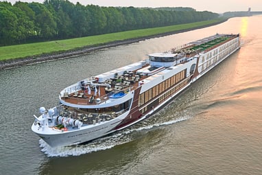 Grosses Flussschiff auf einem ruhigen Fluss bei Sonnenuntergang.