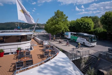 Bootsanlegestelle mit Radfahrern und Reisebus bei schönem Wetter.