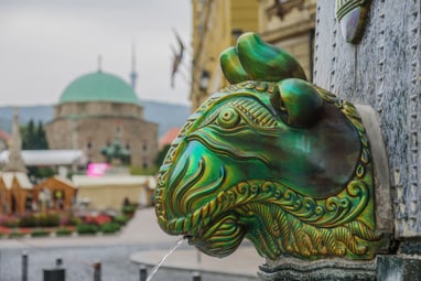 Grüner Brunnenkopf mit monumentaler Kuppel im Hintergrund.