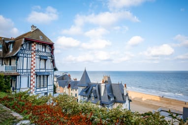 Historisches Gebäude am Meer mit Sandstrand und blauem Himmel.