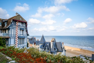 Historisches Gebäude am Meer mit Sandstrand und blauem Himmel.