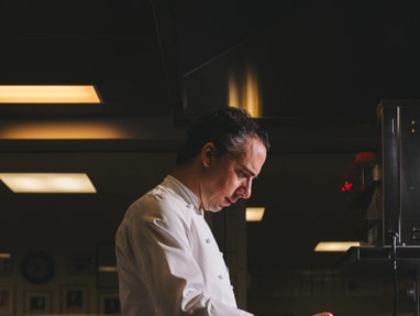 das-excellence-gourmetfestival-10.jpg Koch in weisser Uniform rührt in einem Topf in der Küche.