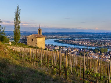 tain-lhermitage.jpg Kapelle auf einem Hügel mit Weinreben und Flussblick bei Sonnenuntergang.