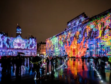 lichterfest-lyon.jpg Bunte Lichtprojektionen auf Gebäuden bei Nacht.
