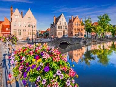 morgenlicht-ueber-dem-historischen-spiegelrei-kanal-in-brueg.jpg Bunte Blumen auf einer Brücke vor historischen Gebäuden am Wasser.