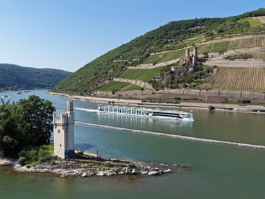 der-hybrid-flussliner-auf-dem-mittelrhein.jpg Flusskreuzfahrtschiff auf dem Rhein mit Burgruine und Weinberg im Hintergrund.