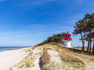 die-autofreie-ostseeinsel-hiddensee-17-km-lang-und-an-der-sc.jpg Kleiner Leuchtturm auf sandiger Düne mit Meer im Hintergrund.