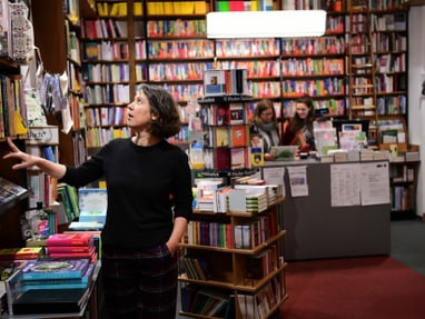 herz-und-heim-ueber-buecherregalen-petra-hartlieb-in-ihrer-b.jpg Frau betrachtet Bücher in einer Buchhandlung.