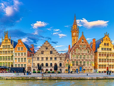 Historische Gebäude am Fluss in Gent bei blauem Himmel.