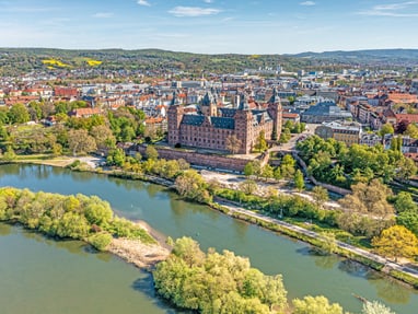 aschaffenburg-schloss-johannisburg-zaehlt-zu-den-bedeutendst.jpg Luftaufnahme einer historischen Stadt mit Schloss und Fluss.