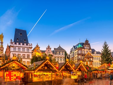 trier.jpg Weihnachtsmarktständen vor historischen Gebäuden bei Abenddämmerung.