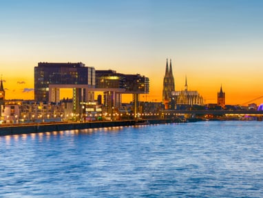auf-backbord-koeln-in-sicht-die-kranhaeuser-und-der-dom.jpg Panorama von Köln bei Sonnenuntergang mit Rhein und Kölner Dom.