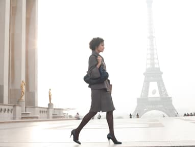 ohlala-tour-de-couture-mit-luisa-rossi-8.jpg Frau in Business-Outfit geht vor dem Eiffelturm entlang.