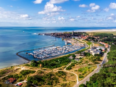 der-yachthafen-de-noordvaarder-im-naturreservat-der-wattenme.jpg Luftaufnahme eines Küstendorfes mit Yachthafen und Strand.