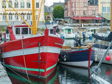 das-beste-frisch-aus-dem-meer-8.jpg Rote und blaue Boote im Hafen neben einem historischen Gebäude.