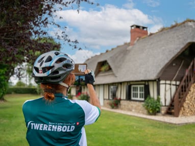 schoene-fotosujets-finden-wir-zuhauf.jpg Person mit Helm fotografiert Fachwerkhaus im Grünen.