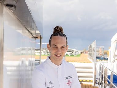 das-excellence-gourmetfestival-10.jpg Person in weissem Outfit sitzt auf einem Bootdeck.