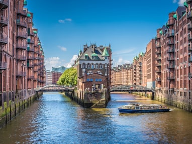 hamburger-speicherstadt-hier-fluestern-die-mauern-von-tee-ka.jpg Kanallandschaft mit historischen Backsteingebäuden und Boot in Hamburg.