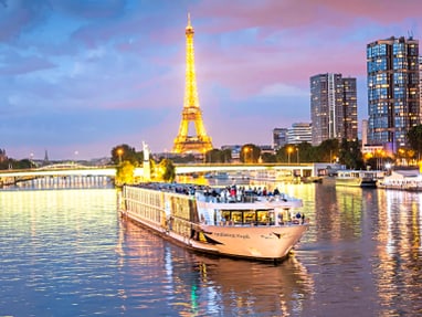 paris.jpg Beleuchtetes Schiff auf der Seine vor Eiffelturm bei Abenddämmerung.