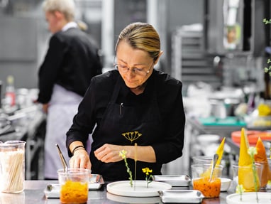 das-excellence-gourmetfestival-10.jpg Koch in schwarzer Schürze, der in einer Restaurantküche arbeitet.