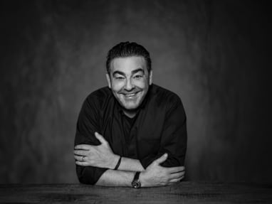 das-excellence-gourmetfestival-10.jpg Lächelnde Person mit verschränkten Armen an einem Tisch.