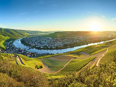 Panorama eines Flusstals mit Stadt bei Sonnenuntergang.