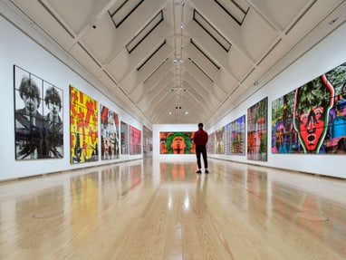 twerenbold_87121.jpg Person in Kunstgalerie mit modernen Gemälden an den Wänden.