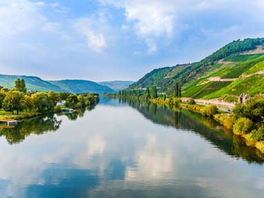 mosel.jpg Flusslandschaft mit Hügeln und Bäumen bei sonnigem Wetter.