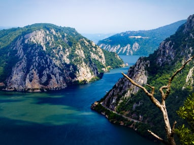 unesco-geopark-djerdap.jpg Fluss fliesst zwischen bewaldeten Bergen.
