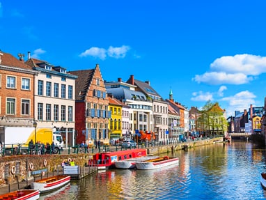 wasserstrassen-von-gent.jpg Stadtansicht mit Kanal und bunten Häusern bei klarem Himmel.