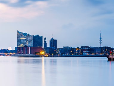 hamburg.jpg Stadtsilhouette bei Dämmerung mit Wasser im Vordergrund.