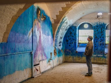 Mann betrachtet Wandgemälde in blauem Raum.
