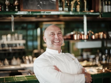 das-excellence-gourmetfestival-4.jpg Mann in weisser Kochkleidung steht in einer Restaurantküche und lächelt in die Kamera.
