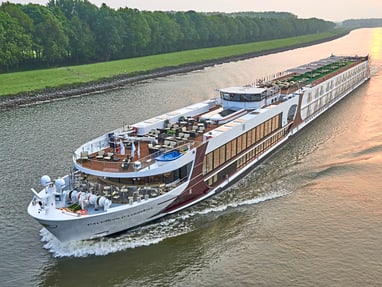 unterwegs-mit-der-excellence-countess.jpg Grosses Flussschiff auf einem ruhigen Fluss bei Sonnenuntergang.