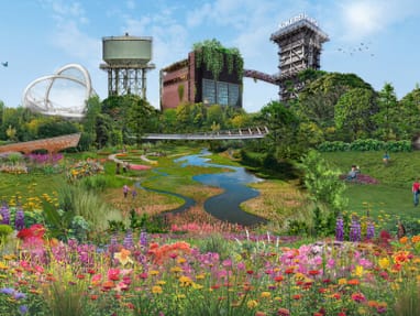 Üppige Gartenlandschaft mit Blumen, einem kleinen Fluss und industriellen Gebäuden im Hintergrund.