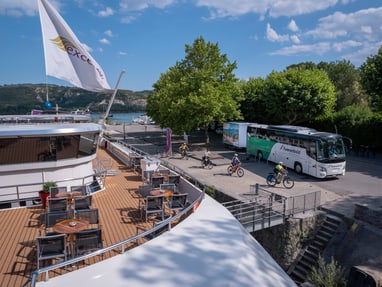 Bootsanlegestelle mit Radfahrern und Reisebus bei schönem Wetter.