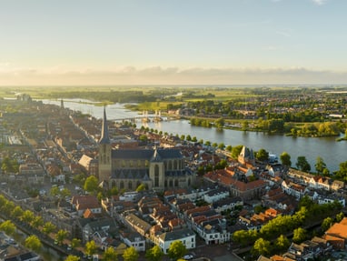 die-ijssel-fuehrt-entlang-historischer-handelsstaedte.jpg Panorama einer Stadt mit Fluss und Kirche im Vordergrund.