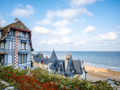 trouville.jpg Historisches Gebäude am Meer mit Sandstrand und blauem Himmel.