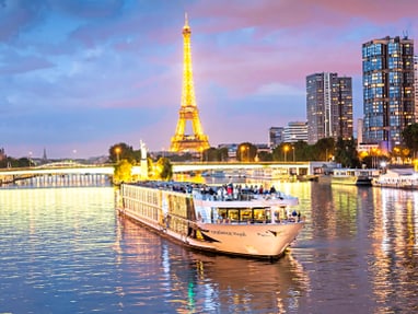 paris.jpg Beleuchtetes Schiff auf der Seine vor Eiffelturm bei Abenddämmerung.