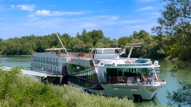 Passagierschiff auf einem Fluss mit Bäumen im Hintergrund.