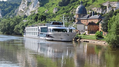 excellence-royal.jpg Flusskreuzfahrtschiff auf der Elbe vor malerischer Hügellandschaft.