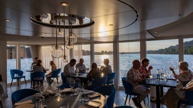 Menschen essen im Flussrestaurant bei Sonnenuntergang.