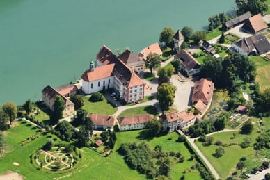schloss-beuggen-historisches-kleinod-direkt-am-rhein.jpg Luftaufnahme eines Schlosses am Fluss mit umliegenden Gebäuden und Gärten.