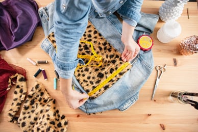 jacken-customisation-workshop-im-atelier-minime-paris.jpg Person misst Stoff auf Jeansjacke mit Massband.