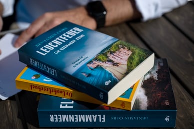 die-normandie-krimis-von-b-cors-abreise-09-08.jpg Person mit Büchern auf einem Tisch.