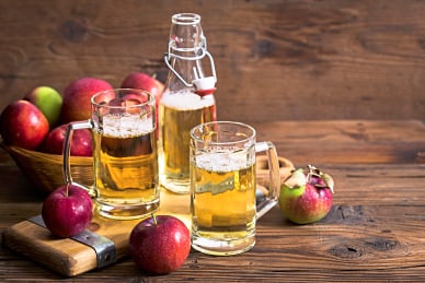 twerenbold_67776.jpg Frische Äpfel und Apfelwein in Gläsern auf Holztisch.
