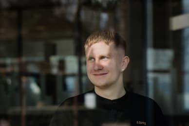 das-excellence-gourmetfestival-10.jpg Person in schwarzer Kleidung steht hinter einer Glasscheibe, umgeben von Innenraumeinrichtung.