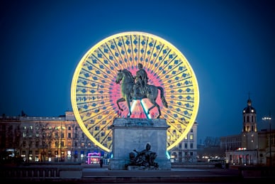 place-bellecour-in-lyon.jpg Reiterstatue vor beleuchtetem Riesenrad bei Nacht.